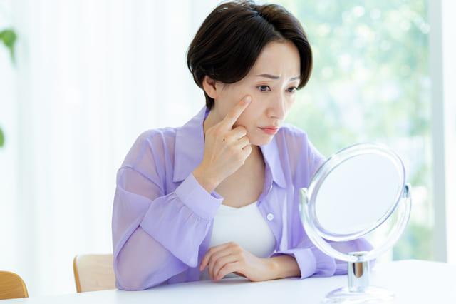 鏡を見ながら顔のほくろを気にしている女性